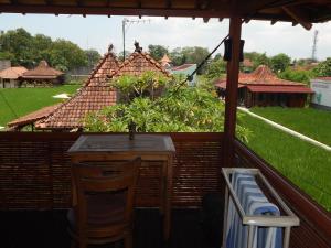 a table and chairs on a balcony with a house at Alamanda Villas, Family Villas, Pool & Local Tours in Yogyakarta