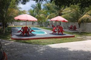a swimming pool with red chairs and umbrellas at Mutary II in Santa Cruz Cabrália