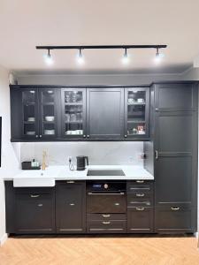 a kitchen with black cabinets and a white counter top at Kapitańska Przystań - basen & sauna & jacuzzi & klimatyzacja & garaż in Dziwnów