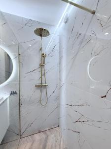 a bathroom with a shower with white marble walls at Kapitańska Przystań - basen & sauna & jacuzzi & klimatyzacja & garaż in Dziwnów