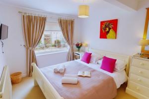 a bedroom with a large bed with pink pillows at CROYDE HALLGREIN 4 Bedrooms in Croyde