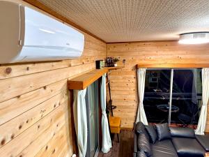 a room with a couch and a tv on a wooden wall at Gen-en Private Hideaway Villa, Izu Forest in Izu