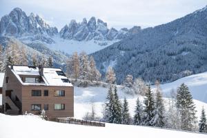 a house in the snow with mountains in the background at Trutscher Häusl in Villnöss - Chalet in den Dolomiten mit Blick auf die Geisler in Funes