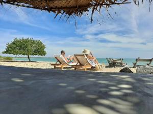 two people sitting in chairs on the beach at Giman Free Beach Resort Pasikuda in Pasikuda