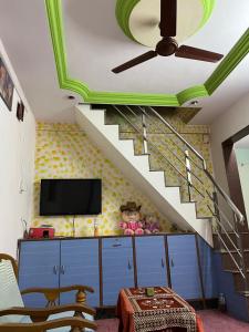 a living room with a staircase and a tv at Peaceful Family Bungalow Near Mahalakshmi Temple in Kolhapur