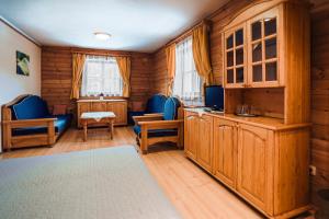 a room with wooden walls and blue furniture and windows at Penzion UNA in Liptovský Ján