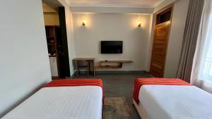 a hotel room with two beds and a television at Iwandaa Boutique Hotel in Nkoanrua