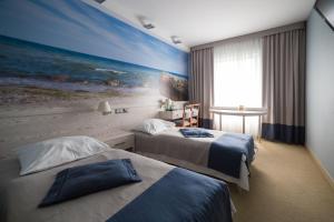ein Hotelzimmer mit 2 Betten und einem Gemälde des Strandes in der Unterkunft Hotel Morski in Gdynia