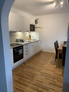 a kitchen with white cabinets and a wooden floor at FeWo Landblick in Hemau