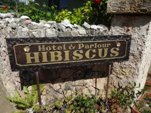 una señal para un hotel y un salón en una pared de piedra en Hotel Hibisicus en Isla Miyako