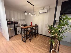 a kitchen with a bar with stools and a refrigerator at Mini Urban Guest House in Kampong Pasang