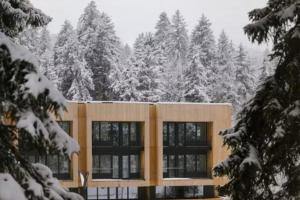 a building covered in snow in front of trees at Koktha-Mitarbi Resort Block 1 Appt 215 in Bakuriani +2 photos