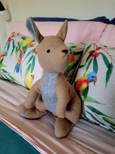 a brown teddy bear sitting on a bed at The Peppercorn Shack in Kingscote