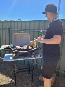 a man is standing next to a grill at The Peppercorn Shack in Kingscote