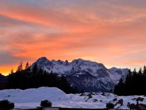 a sunset over a mountain range with snow and trees at Haus Thomas in Werfenweng