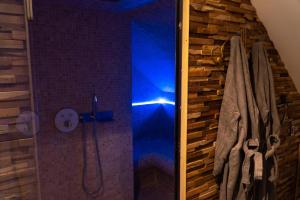 a shower with a blue light in a bathroom at Love Room Evasion Jacuzzi Sauna Hamamm in Saint-Cyr-sur-Loire