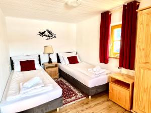 two beds in a room with red curtains at Haus Thomas in Werfenweng