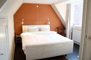 a bedroom with a large white bed with an orange wall at Abeelboom B and B in Middelburg
