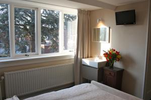 a bedroom with a bed and a sink and windows at Abeelboom B and B in Middelburg