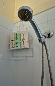 a shower head with four bottles on a shelf at Brownlow Beach Shack in Kingscote