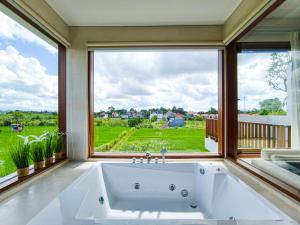 a bath tub in a room with a large window at Mountain Sunshine Private Villa in Darmasaba