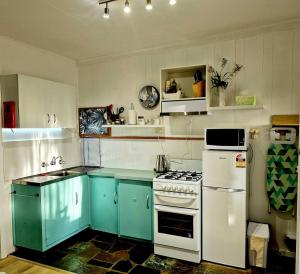 a kitchen with blue cabinets and a white stove top oven at Brownlow Beach Shack in Kingscote