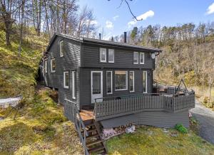 a black house on a hill with a deck at Look at this view! 3 BR house overlooking Hardangerfjorden in Kvam