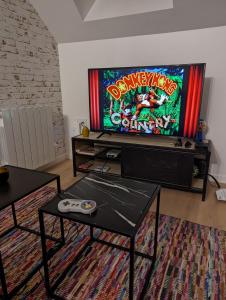 a living room with a video game on the tv at Le Studio Neo-Retro in Digoin