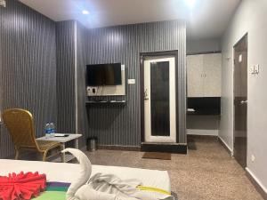 a room with a bed and a tv and a table at Hotel Vaishnavi in Hyderabad