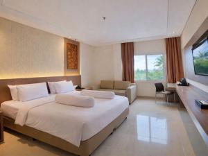 a hotel room with a large bed and a desk at Nevada Ketapang Hotel in Ketapang +56 photos