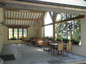 a dining room with tables and chairs and windows at L'orchidée in Rochehaut