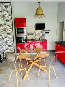 a table and chairs in a kitchen with red cabinets at L entre deux charentes in Montils