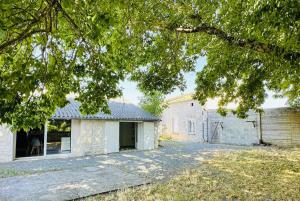 an old white brick house with a tree at L entre deux charentes in Montils