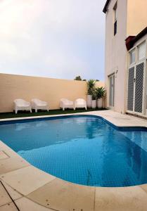 a swimming pool with two chairs and a building at Number 4 Smugglers Inn in Victor Harbor