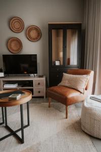 a living room with a tv and a chair and a table at IBella's at The Urban in Pretoria