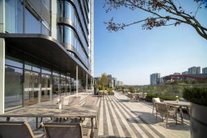 a patio on the side of a building with tables and chairs at Novotel Chengdu Lige in Chengdu