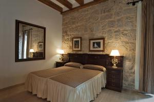 1 dormitorio con cama y pared de piedra en Señorio de Olmillos, en Olmillos de Sasamón