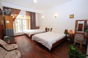 a hotel room with two beds and a mirror at Dan Chi Hotel in Da Lat