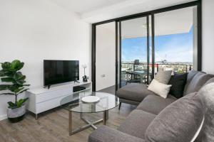 a living room with a couch and a tv at Soda Apartments by CLLIX in Brisbane