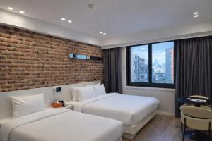 two beds in a hotel room with a brick wall at Haeundae HaeRium Hotel in Busan
