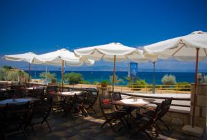 a restaurant with tables and white umbrellas at Kiwi Kastle in Nea Fokea