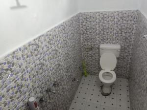 a bathroom with a toilet and a tiled wall at Hotel Amit Kedar Dham in Sirsi