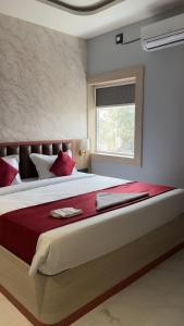 a bedroom with a large bed with red sheets and a window at Sova Premium in Jagatsinghapur