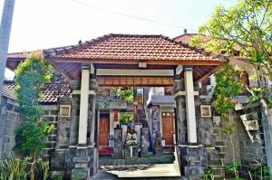 a house with a stone wall and a roof at Yulia 2 Homestay Sanur in Sanur