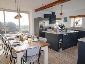 a kitchen with a dining table and a kitchen with blue cabinets at Pastures Barn in Leek