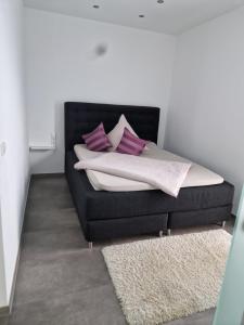 a bed with purple and white pillows and a rug at Brenzapartments Heidenheim in Heidenheim an der Brenz