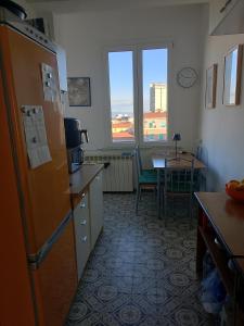 a kitchen with a refrigerator and a table and a window at TCEM camera in attico 6 no ascensore in Piombino