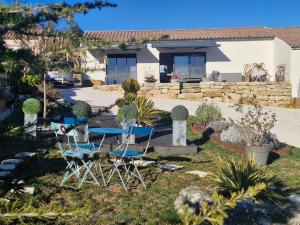 a house with two chairs and a table in the yard at Le cottage Bleu du Sud in Saint-Étienne-les-Orgues