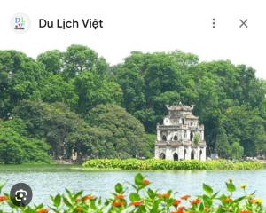 a building in the middle of a lake with trees at An's Home in Hanoi