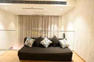 a black couch sitting in a room with pillows at Let's Loft - A Premium Luxury Style Duplex Living in Gurgaon +35 photos